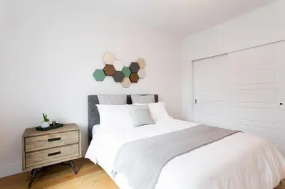 a bedroom with a white bed and a wooden night stand at Hip, Stylish Apartment in Little Italy by Den Stays A in Montréal