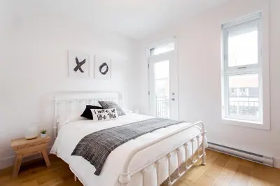 a white bedroom with a white bed and two windows at Hip, Stylish Apartment in Little Italy by Den Stays A in Montréal