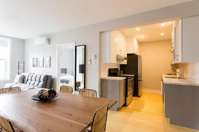 a kitchen and living room with a wooden table in a room at Trendy Little Italy 3 Bedroom Condo Free parking in Montréal