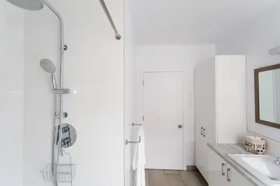 a white bathroom with a shower and a sink at Trendy Little Italy 3 Bedroom Condo Free parking in Montréal