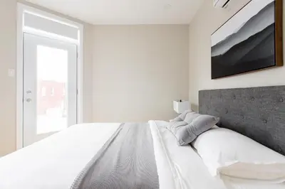 a white bedroom with a large bed and a window at Trendy Little Italy 3 Bedroom Condo Free parking in Montréal