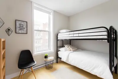 a bedroom with two bunk beds and a chair at Trendy Little Italy 3 Bedroom Condo Free parking in Montréal