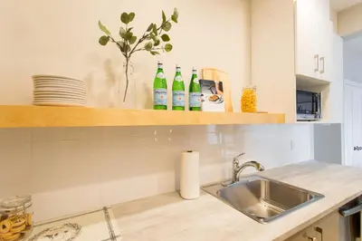 a kitchen with a sink and bottles on a shelf at Trendy Little Italy 3 Bedroom Condo Free parking in Montréal