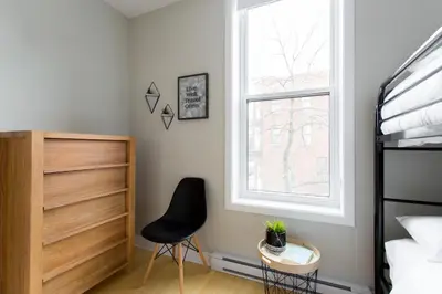 a bedroom with a black chair and a window at Trendy Little Italy 3 Bedroom Condo Free parking in Montréal