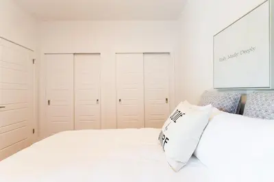 a bedroom with white cabinets and a white bed with a pillow at Little Italy Spacious 2 Bedroom Condo Free Parking in Montréal