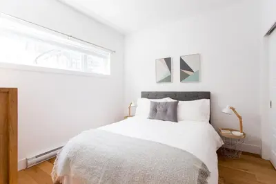 a white bedroom with a large bed with a window at Little Italy Spacious 2 Bedroom Condo Free Parking in Montréal