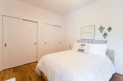 a white bedroom with a bed and two closets at Little Italy Spacious 2 Bedroom Condo Free Parking in Montréal