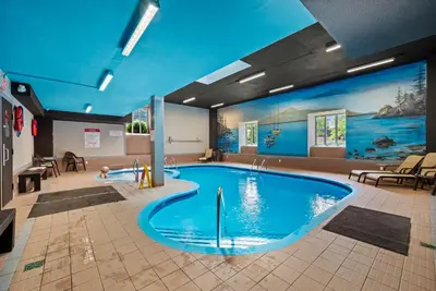 a large swimming pool in a room with tables and chairs at O'Berge du Village C304 - Bord de l'eau in Magog-Orford