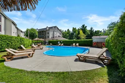 a swimming pool with chaise lounge chairs around it at O'Berge du Village C304 - Bord de l'eau in Magog-Orford