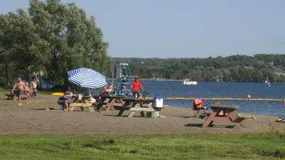 a group of people sitting at a picnic table with an umbrella at O'Berge du Village C304 - Bord de l'eau in Magog-Orford