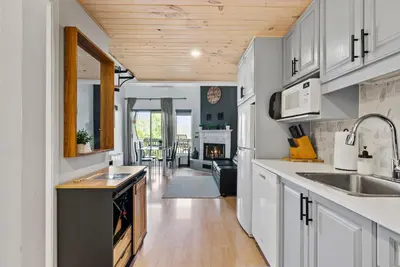 a kitchen with white cabinets and a wooden ceiling at O'Berge du Village C304 - Bord de l'eau in Magog-Orford