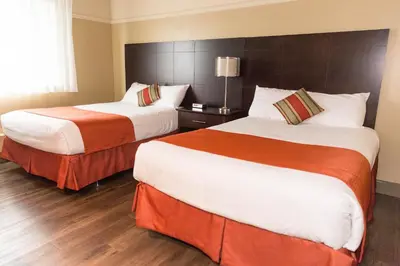 a hotel room with two beds with orange and white sheets at Hotel-Resto-Bar Le Journel in Saint-Joseph-de-Beauce