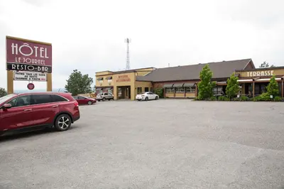 a red car parked in a parking lot in front of a store at Hotel-Resto-Bar Le Journel in Saint-Joseph-de-Beauce