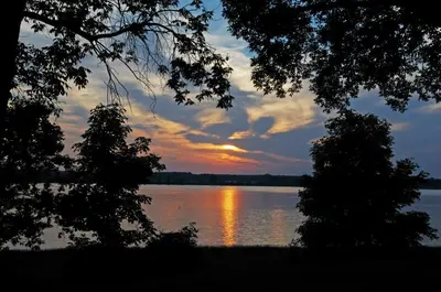 a sunset over a body of water with trees at Motel Le Charentais in Sorel
