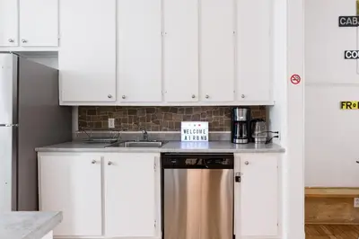 a kitchen with white cabinets and a stainless steel dishwasher at Apartments Near Montreal Olympic Park in Montréal
