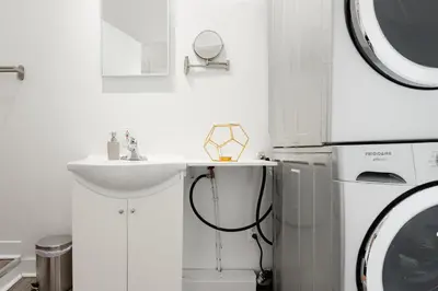 a white bathroom with a sink and a washing machine at Apartments Near Montreal Olympic Park in Montréal