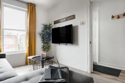 a living room with a couch and a tv on a wall at Apartments Near Montreal Olympic Park in Montréal