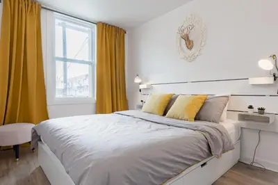 a white bedroom with a large bed and a window at Apartments Near Montreal Olympic Park in Montréal