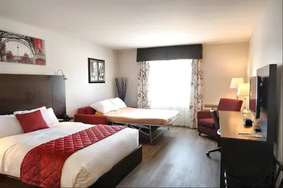 a hotel room with a bed and a desk and a room at Hôtel Le Floral in Sherbrooke