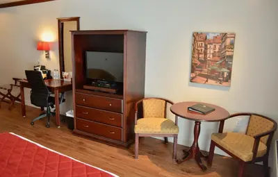 a living room with a tv and a table and chairs at Hôtel Le Floral in Sherbrooke