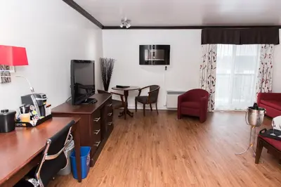 a living room with a desk and a table with a tv at Hôtel Le Floral in Sherbrooke