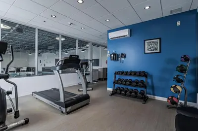 a gym with exercise equipment and a blue wall at Holiday Inn Express Hotel & Suites Saint - Hyacinthe by IHG in Saint-Hyacinthe