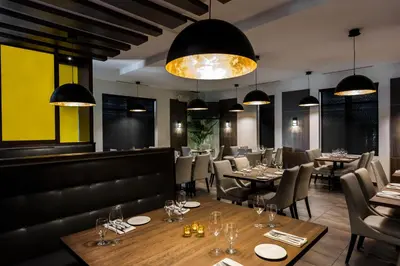 a dining room with tables and chairs and lights at Imperia Hôtel et Suites Terrebonne in Terrebonne