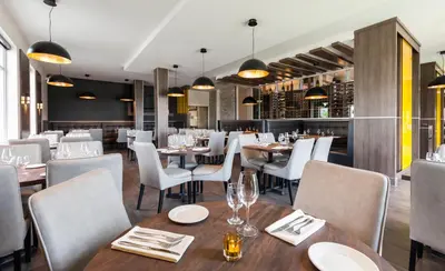 a restaurant with wooden tables and white chairs at Imperia Hôtel et Suites Terrebonne in Terrebonne