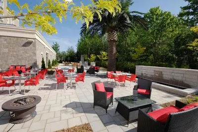 a patio with tables and chairs and a palm tree at Imperia Hôtel et Suites Terrebonne in Terrebonne
