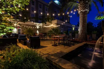 a patio with tables and chairs and lights at night at Imperia Hôtel et Suites Terrebonne in Terrebonne
