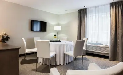 a dining room with a table and white chairs at Imperia Hôtel et Suites Terrebonne in Terrebonne