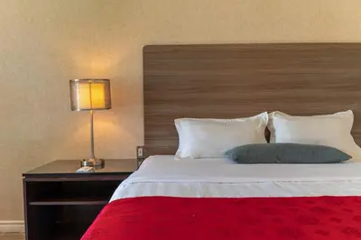 a bedroom with a large bed with a wooden headboard at Hotel Cowansville in Cowansville