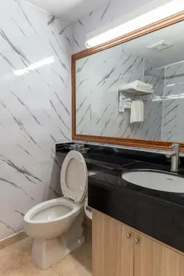 a bathroom with a toilet and a sink and a mirror at Hotel Cowansville in Cowansville