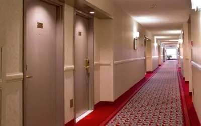 a long hallway with a red carpeted floor and doors at Hotel Ruby Foo's in Montréal