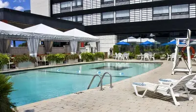 a swimming pool with white chairs and a building at Hotel Ruby Foo's in Montréal