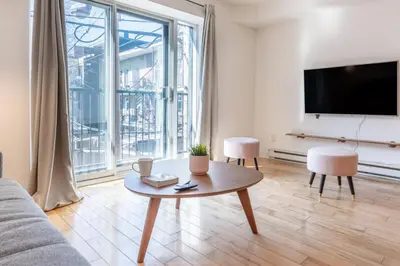 a living room with a table and a large window at Alywin Apartments in Hochelaga in Montréal
