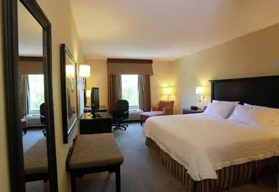 a hotel room with a bed and a chair at Hampton Inn & Suites Laval in Laval