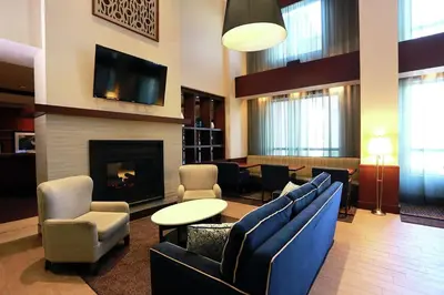 a lobby with a fireplace and chairs and a tv at Hampton Inn & Suites Laval in Laval
