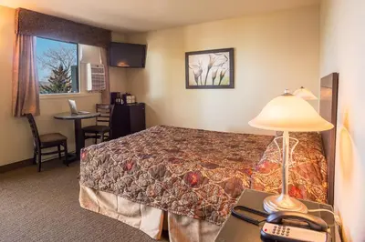 a hotel room with a bed and a table with a lamp at Motel Du Fleuve in Brossard