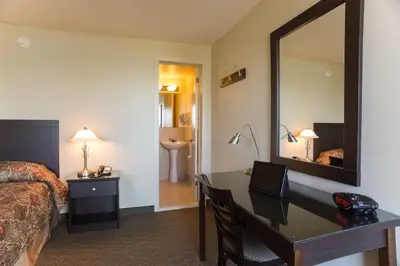 a hotel room with a desk and a bed and a mirror at Motel Du Fleuve in Brossard
