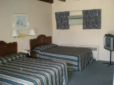 a hotel room with two beds and a television at Motel Seigneurie de Vaudreuil in Vaudreuil-Dorion