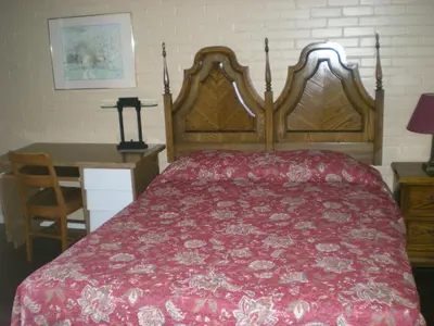 a bedroom with a large bed with a red bedspread at Motel Seigneurie de Vaudreuil in Vaudreuil-Dorion