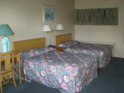 a hotel room with two beds and a table at Motel Seigneurie de Vaudreuil in Vaudreuil-Dorion