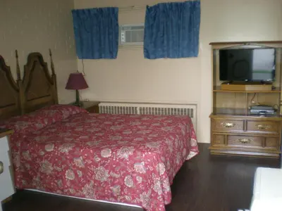 a bedroom with a bed and a flat screen tv at Motel Seigneurie de Vaudreuil in Vaudreuil-Dorion