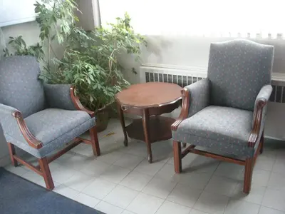 two chairs and a table in a room with a plant at Motel Seigneurie de Vaudreuil in Vaudreuil-Dorion