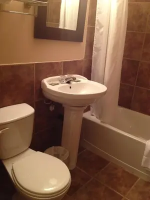 a bathroom with a sink and a toilet and a tub at Chomedey Inn in Laval