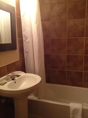 a bathroom with a sink and a toilet and a tub at Chomedey Inn in Laval