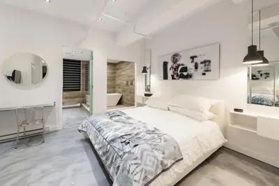 a white bedroom with a bed and a mirror at The Holland Hotel by Simplissimmo in Montréal