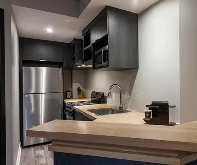 a kitchen with a stainless steel refrigerator and a sink at Imperia Hôtel et Suites Boucherville in Boucherville