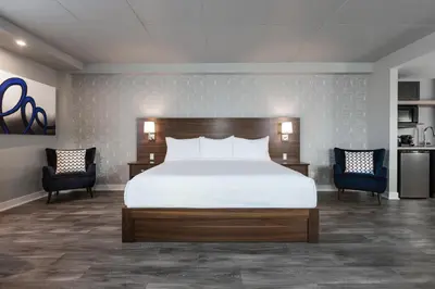a bedroom with a large bed and two chairs at Imperia Hôtel et Suites Boucherville in Boucherville